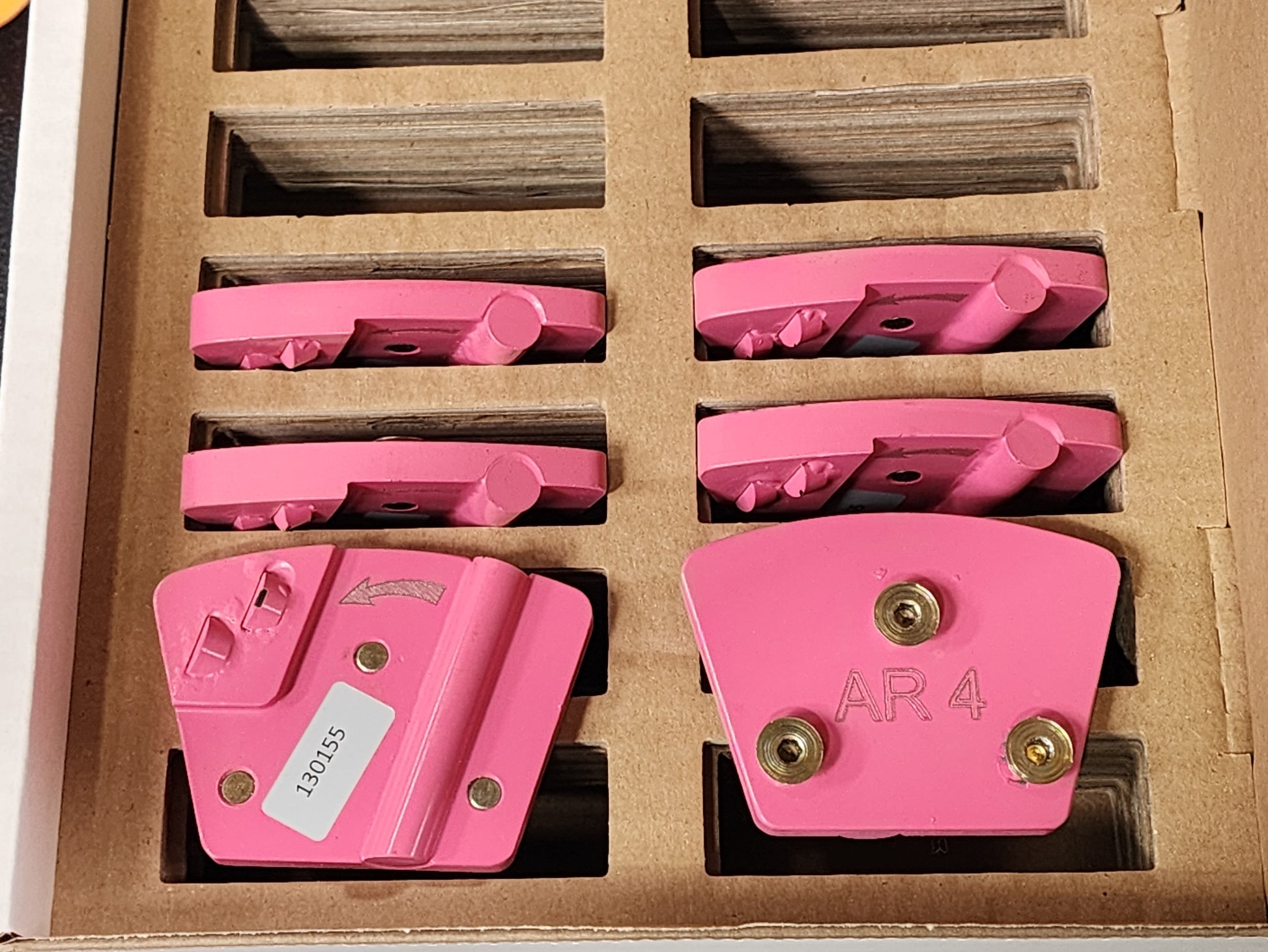 A set of pink, wedge-shaped industrial diamond grinding segments arranged in a cardboard tray, with the bottom-right segment labeled "AR 4".