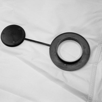 A close-up shot of a black rubber inlet ring on a white vacuum filter bag, featuring an attached circular sealing cap on a tether.