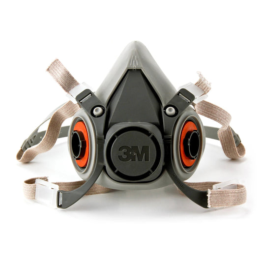 A 3M half-face respirator mask with a gray and black facepiece, featuring orange filter canisters and beige elastic straps, shown on a white background.