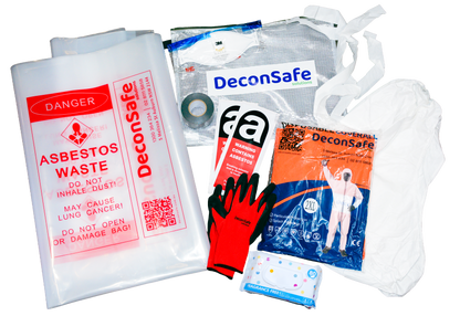 An overhead view of a DeconSafe asbestos safety kit with labeled waste bags, a respirator, and warning labels. It also includes protective gloves, a disposable coverall, a hood, duct tape, and wet wipes.