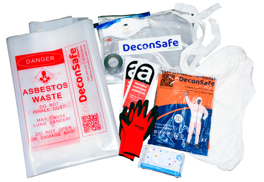 An overhead view of a DeconSafe asbestos safety kit with labeled waste bags, a respirator, and warning labels. It also includes protective gloves, a disposable coverall, a hood, duct tape, and wet wipes.